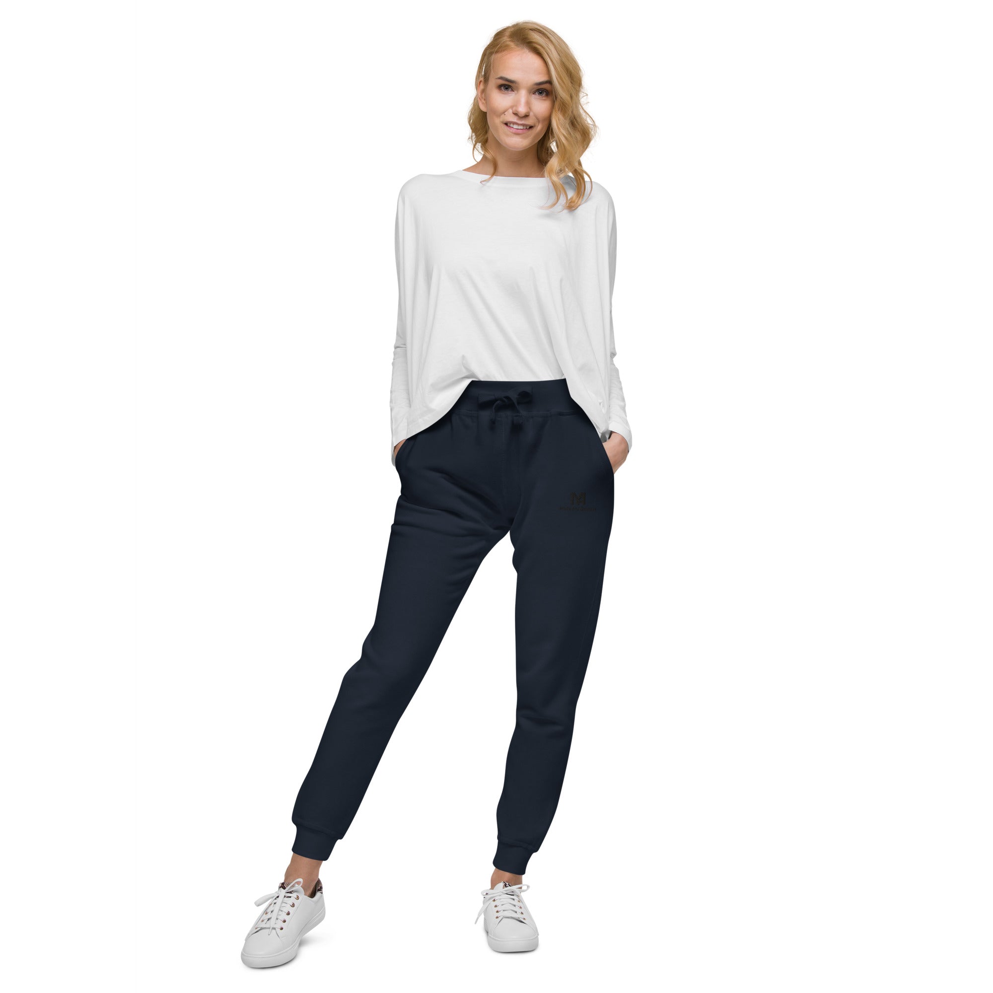 Woman wearing a white top and navy jogger pants on a white background